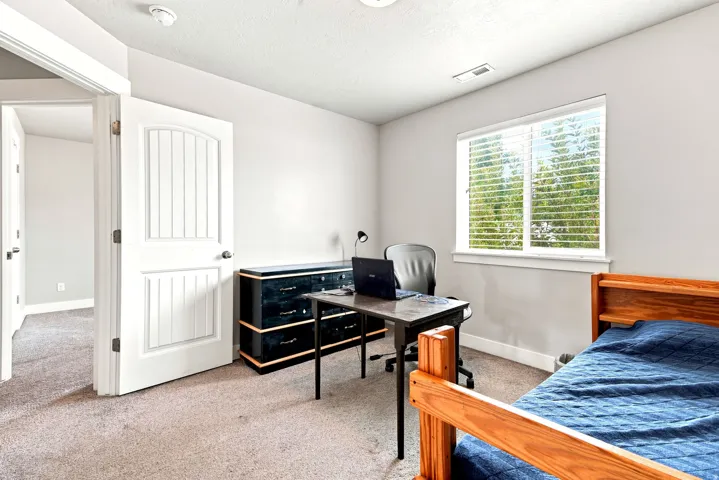 Bedroom featuring neutral carpeting, light-toned walls, and a window with horizontal blinds