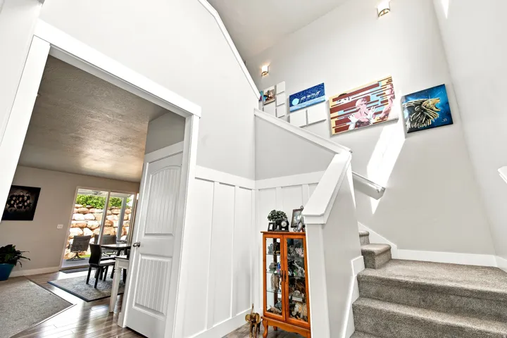 Two-story entryway with board and batten wainscoting, carpeted staircase, and wood-finish flooring