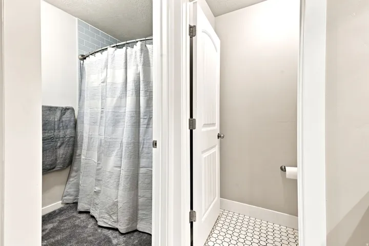 Bathroom featuring a shower with light blue subway tile surround and a separate area with white hexagonal mosaic tile flooring
