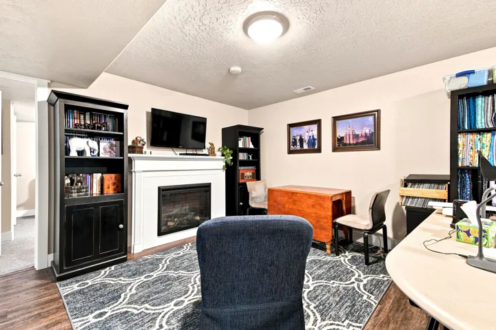 Living area featuring wood-finish flooring, a white mantel fireplace, and recessed lighting