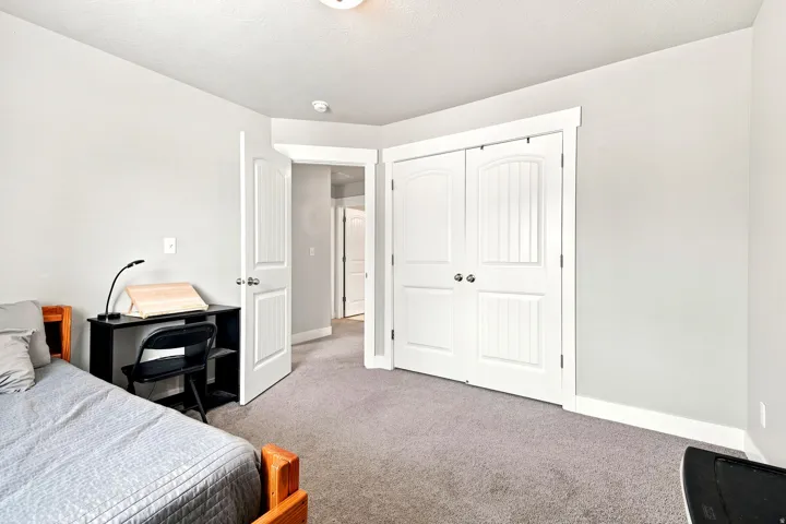 Carpeted room with a double-door closet featuring arched panel details, white trim, and light gray walls