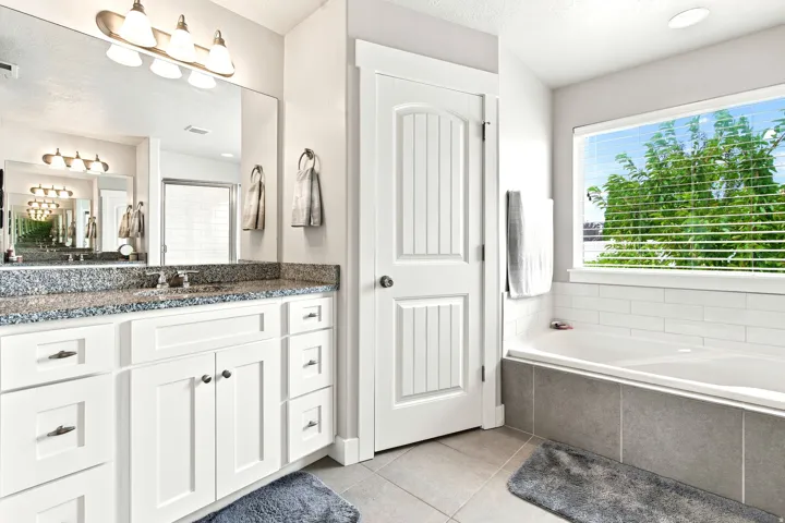 Dual-sink vanity featuring white shaker cabinetry and a speckled stone countertop