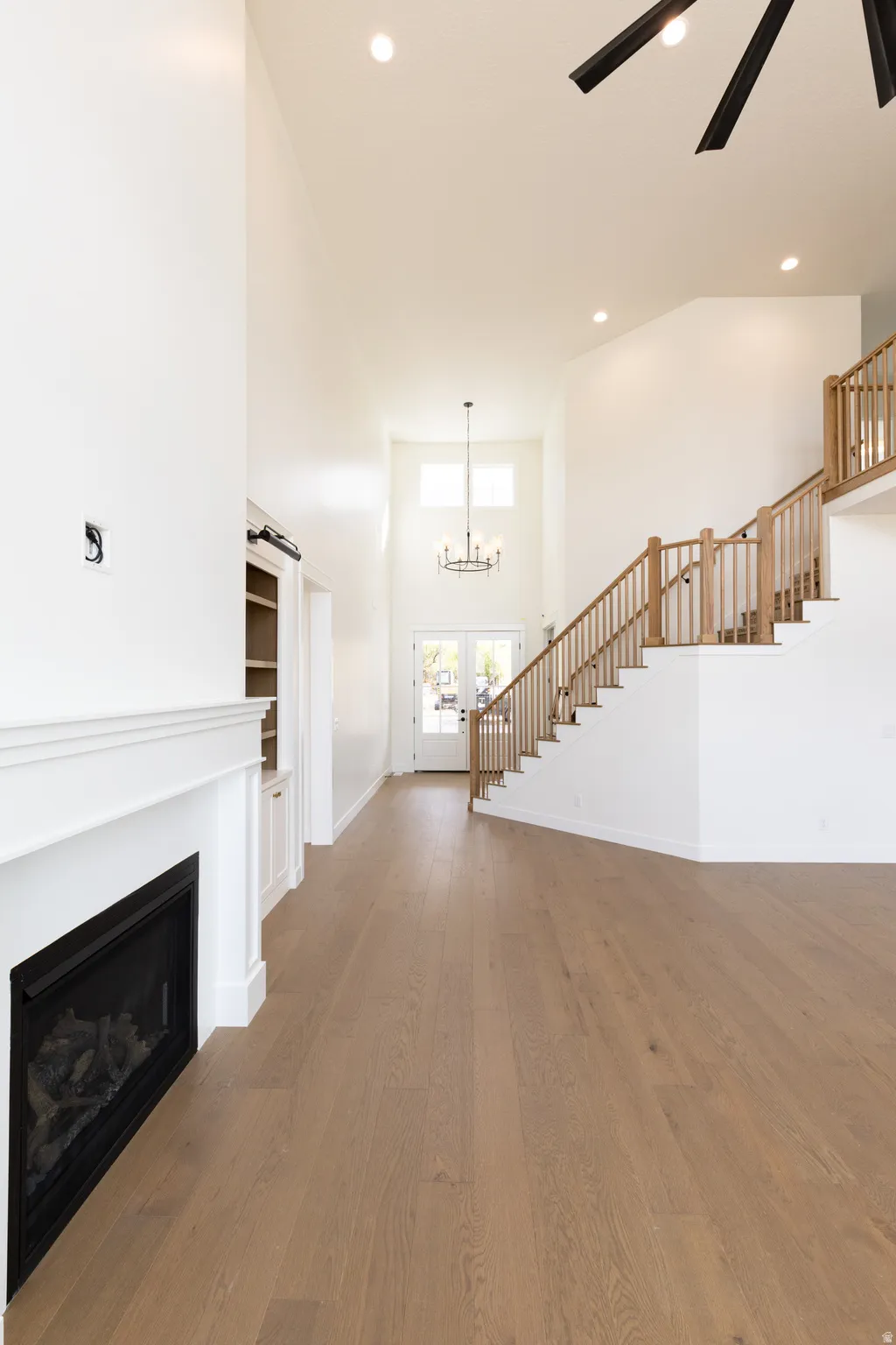 Vaulted ceilings, wood-finish flooring, built-in fireplace, natural wood staircase, and an entry chandelier