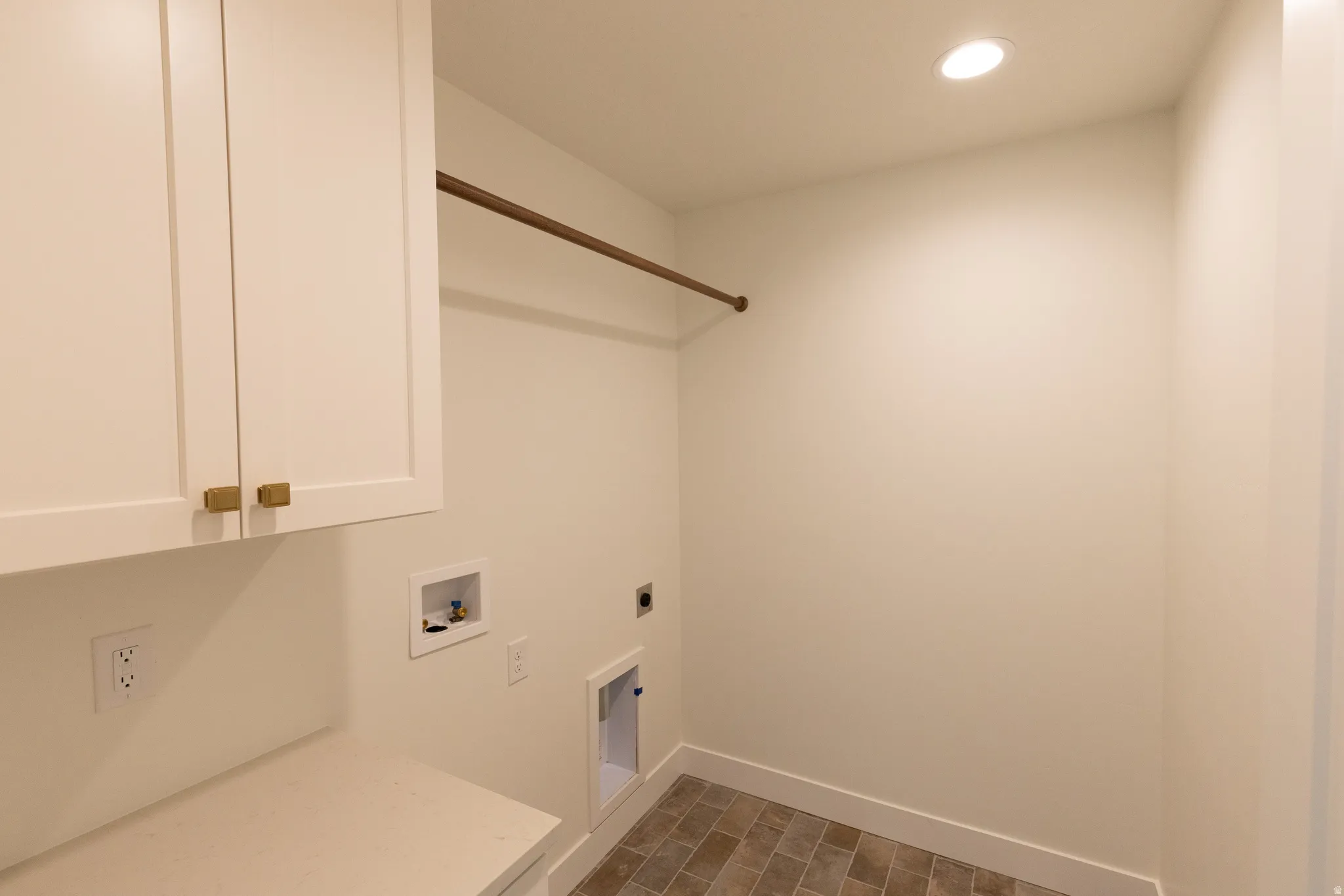 White shaker-style cabinetry with gold-tone hardware, a built-in hanging rod, a light-toned countertop, recessed ceiling lighting, and tiled flooring
