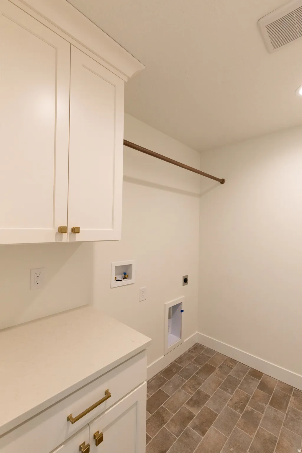 Custom cabinetry with gold-tone hardware, white countertop surface, and brown rectangular floor tiles