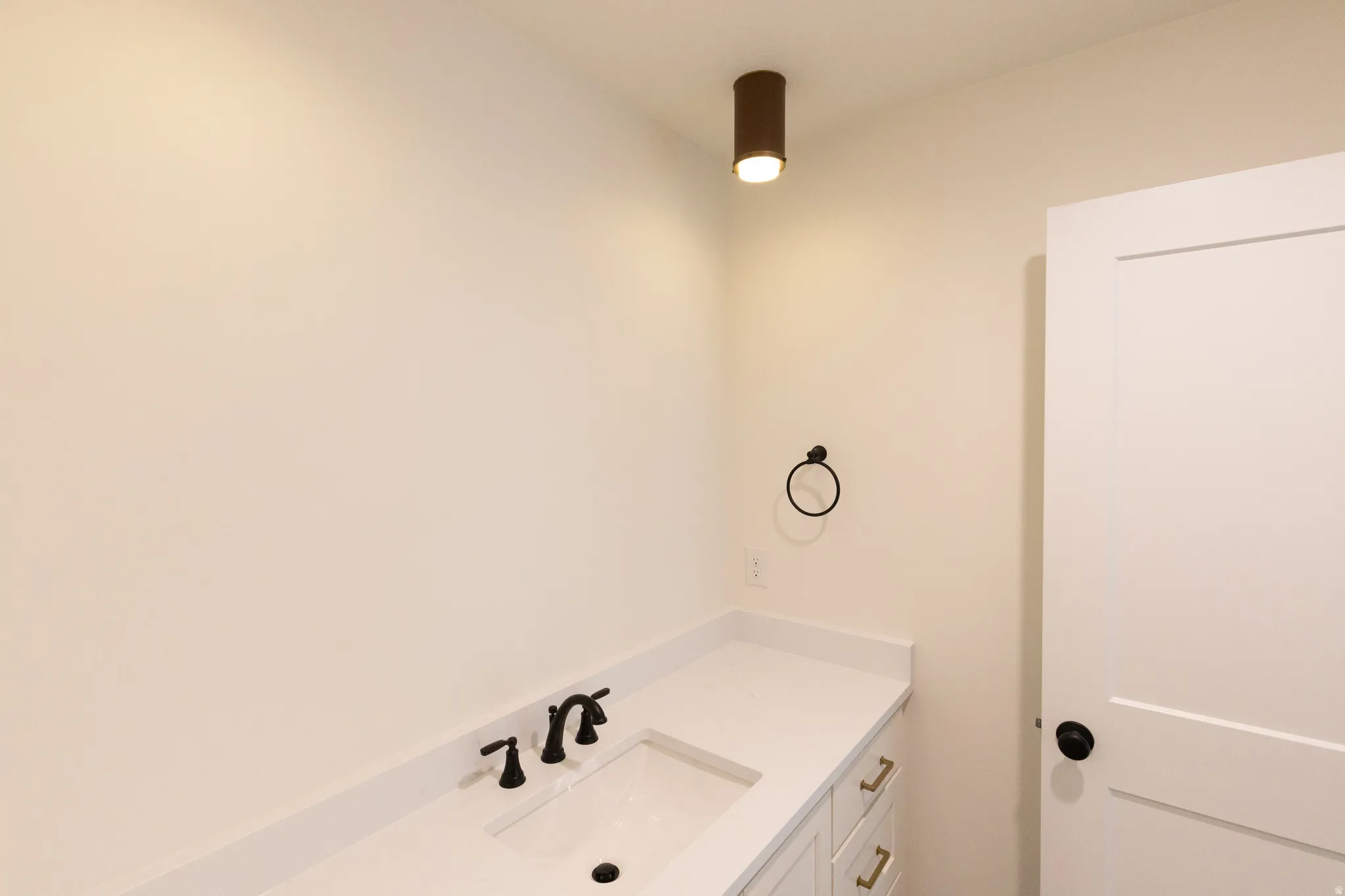 White vanity with an integrated sink, matte black faucet, and brass hardware