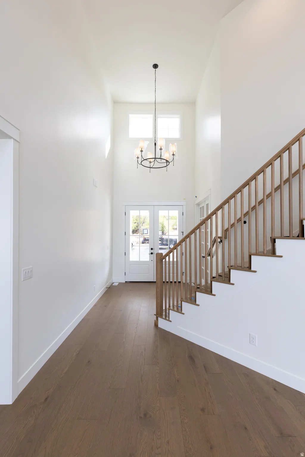 Two-story foyer with high ceilings, wood-finish flooring, and a chandelier