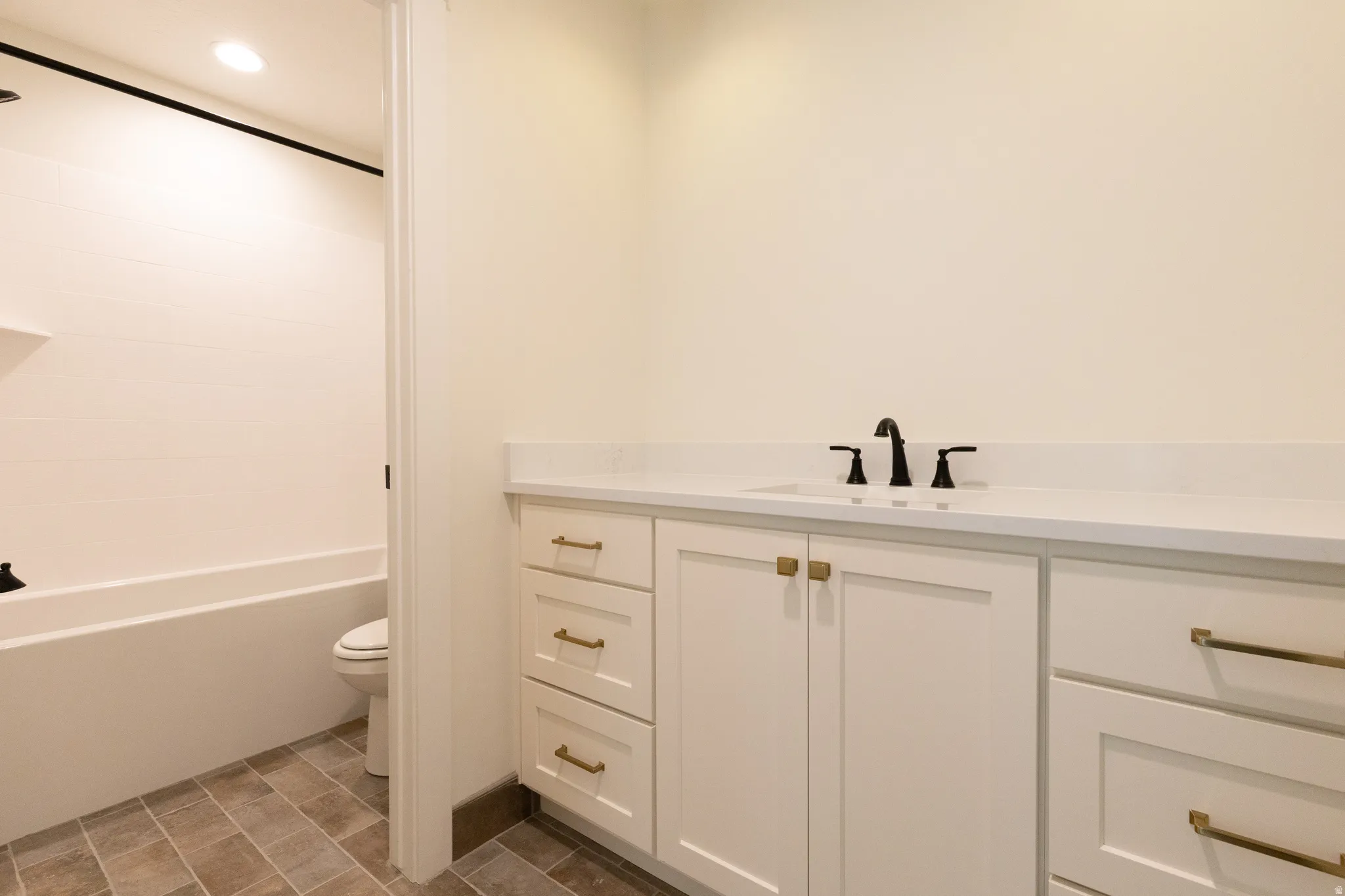White shaker cabinetry featuring gold-tone hardware, white countertop, and dark-tone fixtures