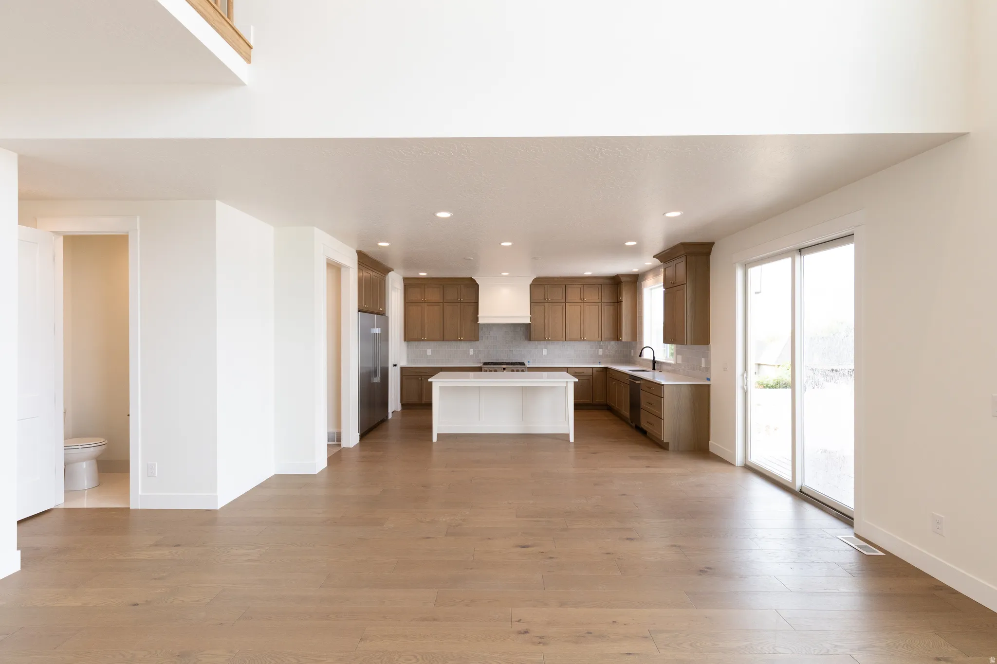 Open-concept living area with wood-finish flooring, recessed lighting, and a sliding glass door