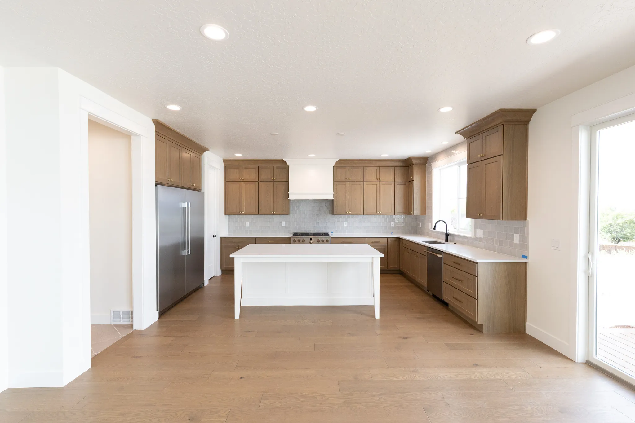 Kitchen featuring recessed lighting, a central island, wood-finish cabinetry, stainless steel appliances, and a sliding glass door