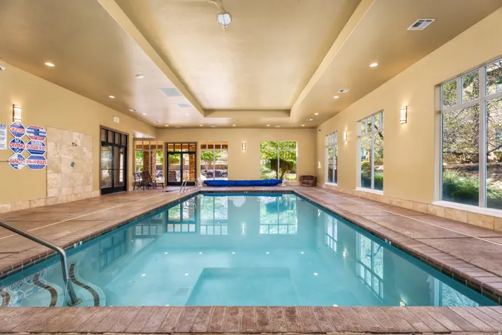 Indoor swimming pool featuring a built-in step entry, perimeter coping, and multiple large windows