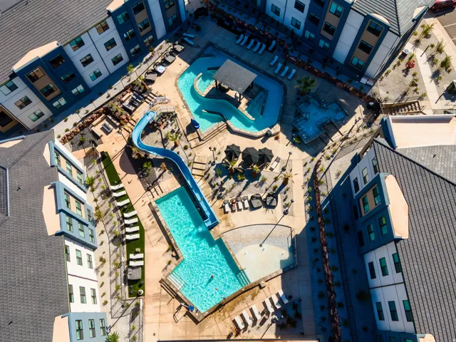Central courtyard featuring a swimming pool with a slide, a lazy river, a spa, and multiple lounge areas