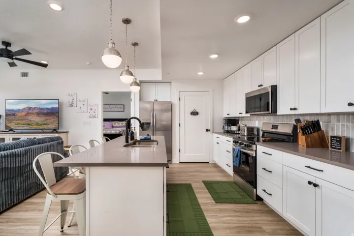 Modern kitchen featuring white shaker cabinetry, stainless steel appliances, a light gray countertop, and a tiled backsplash