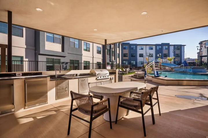 Covered outdoor kitchen featuring a built-in grill, sink, and stainless steel refrigeration units