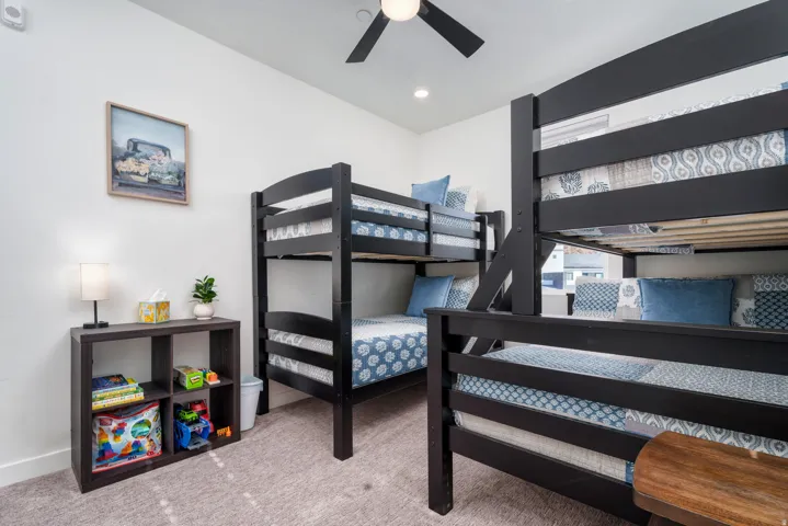 Spacious room featuring two dark wood-finish bunk beds, a ceiling fan with integrated lighting, and recessed overhead lighting