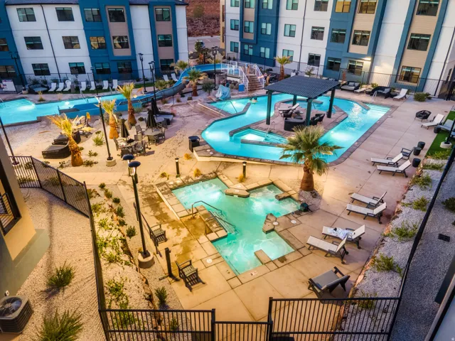 Expansive aquatic amenity area featuring multiple illuminated pools, a flowing water feature, and a raised spa