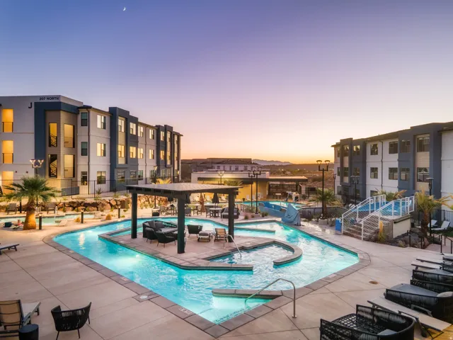 Expansive outdoor common area featuring a multi-level swimming pool, integrated spa, and shaded lounge spaces