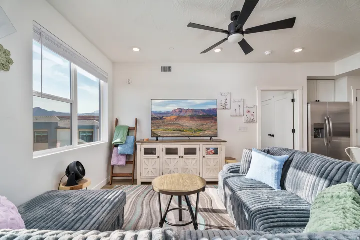 Open-concept living area featuring a large window, a ceiling fan with integrated lighting, and recessed ceiling lights