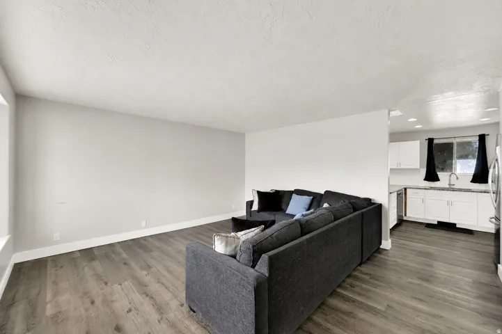 Spacious living area featuring wood-finish flooring, light-toned walls, and a large window