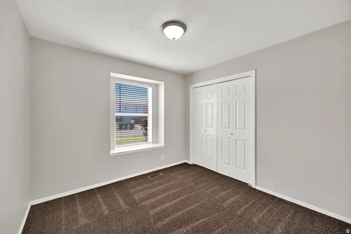 Interior room featuring neutral wall paint, brown patterned carpeting, and a white bi-fold closet