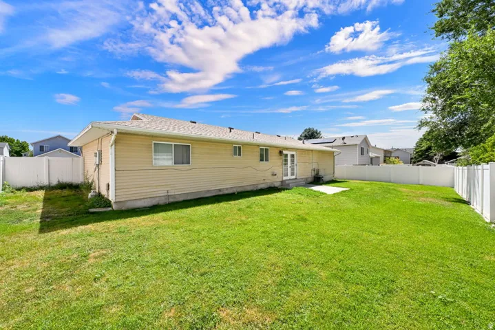 Expansive green lawn surrounds the property, complemented by a white vinyl privacy fence