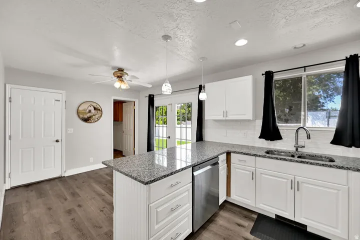 Kitchen featuring white cabinetry, granite countertops, stainless steel dishwasher, and wood-finish flooring