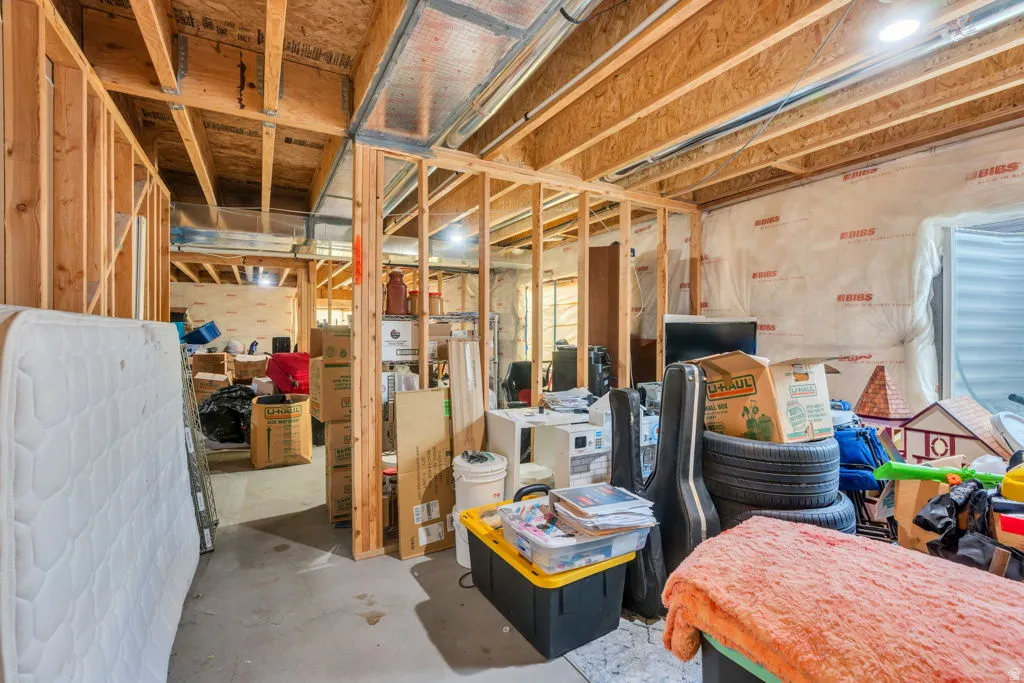 Unfinished basement space featuring exposed wood framing, concrete flooring, and visible ductwork