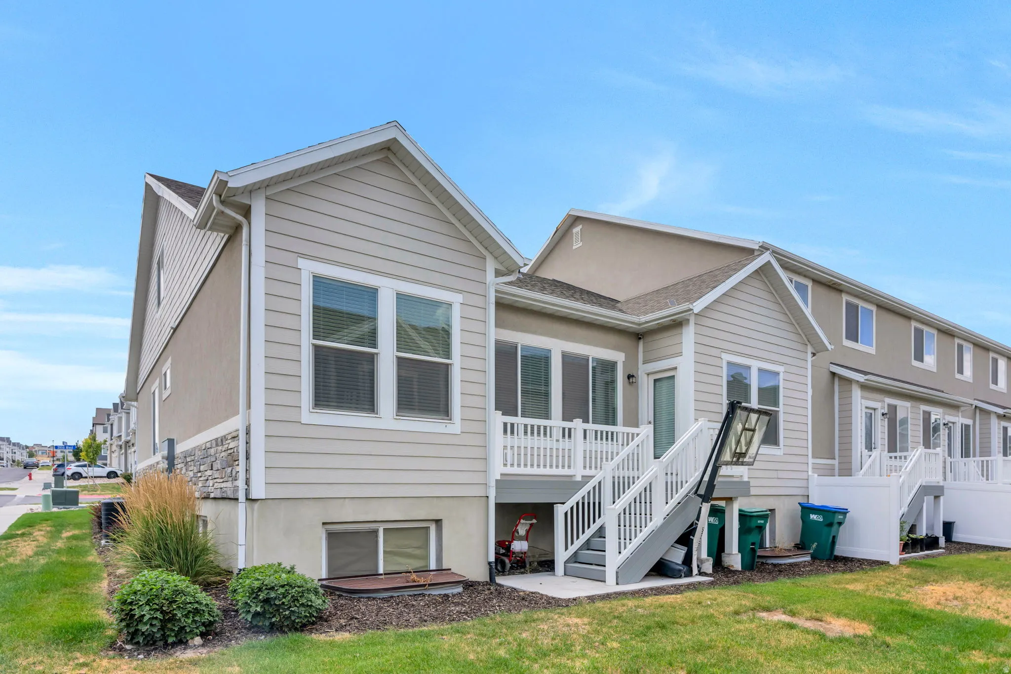 Rear exterior featuring a deck with white railings, a lower concrete patio, and a grass lawn