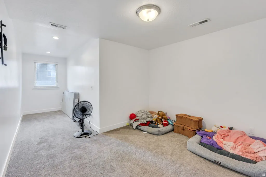Carpeted room with white painted walls and a window with horizontal blinds