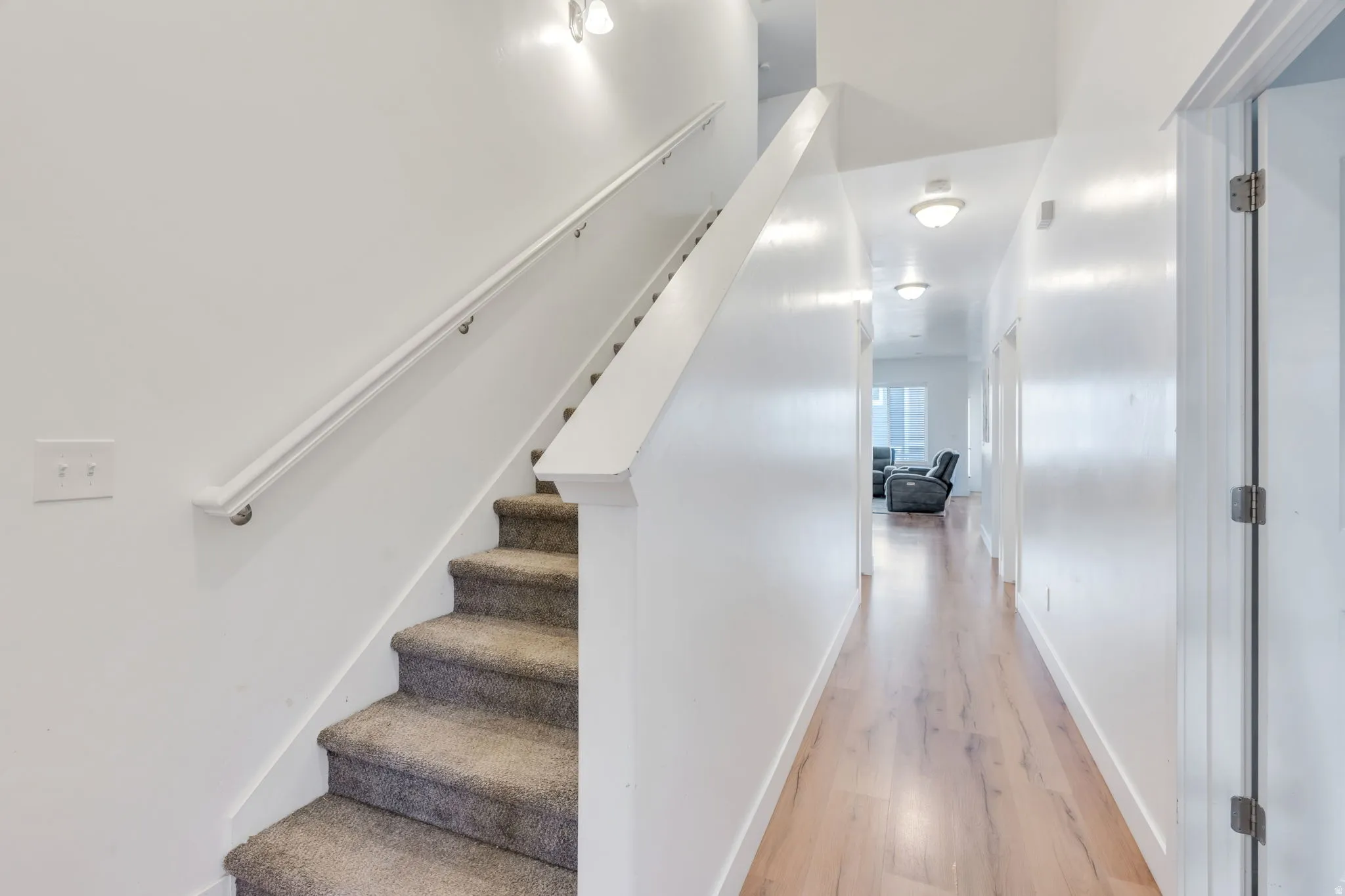 Carpeted staircase with white handrail and wall-mounted light fixtures