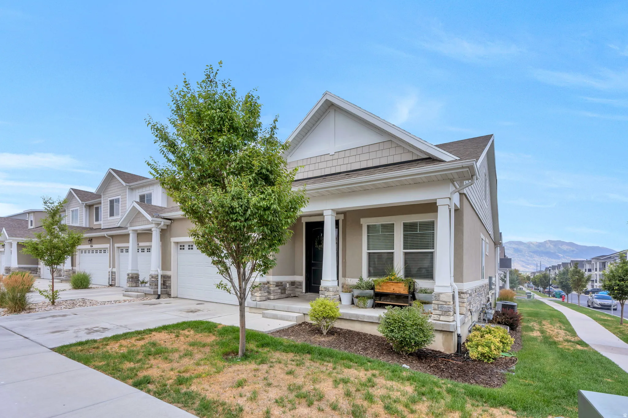 Contemporary townhome featuring a front porch with white columns, a stone facade, and horizontal siding