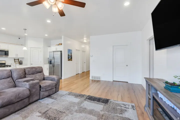 Open-concept living space featuring wood-finish flooring, recessed lighting, and a ceiling fan
