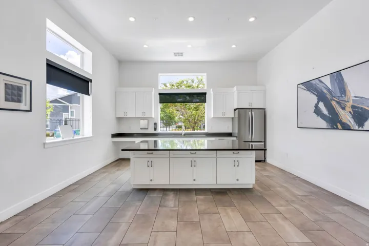 Kitchen featuring an expansive island with a dark countertop, white cabinetry, and stainless steel refrigerator