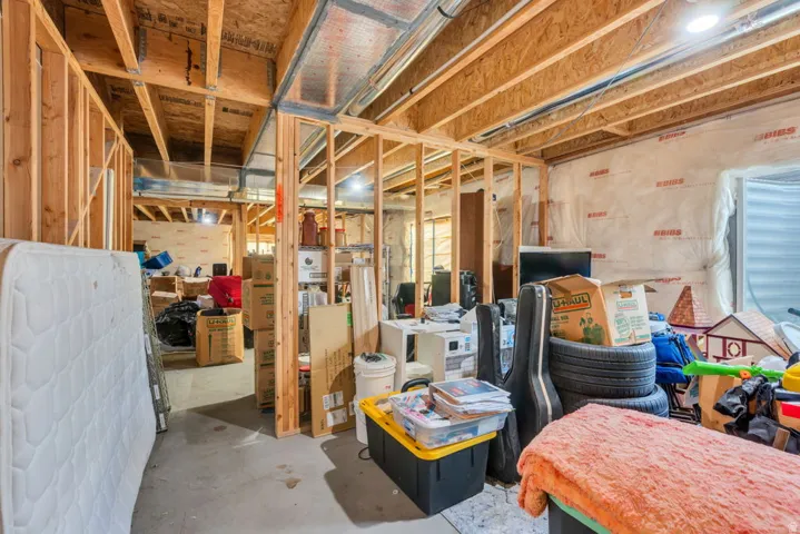 Unfinished basement space featuring exposed wood framing, concrete flooring, and visible ductwork