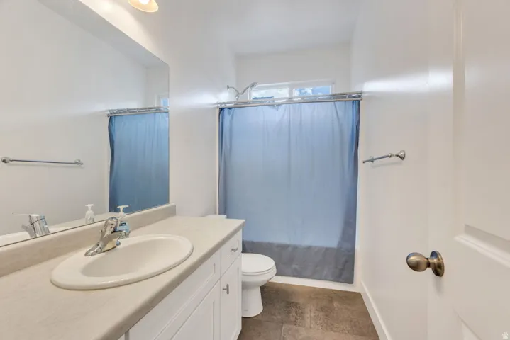 Bathroom featuring a single vanity with an integrated sink, white cabinetry, and a light-toned countertop
