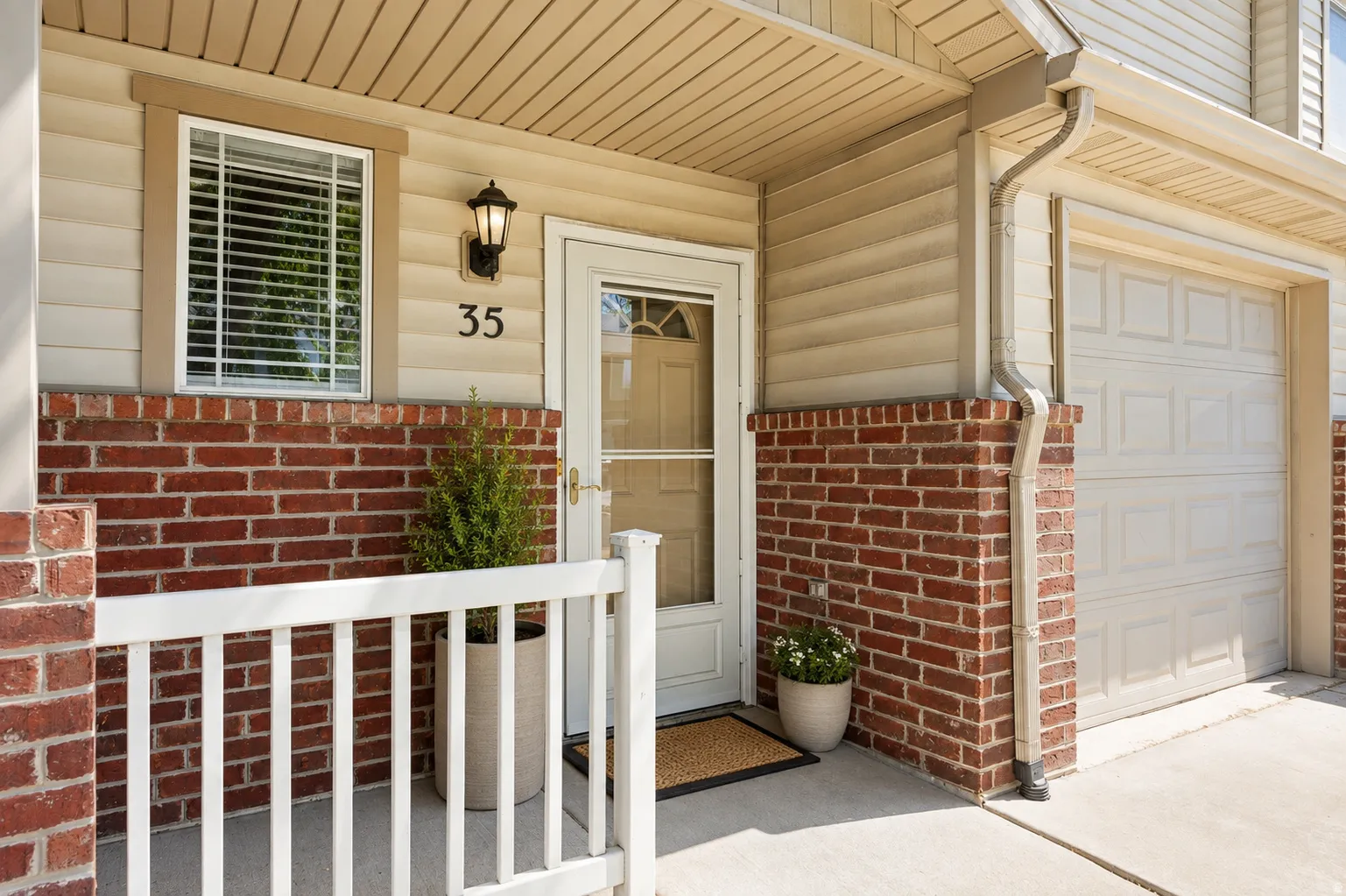 Front entrance featuring brick wainscoting and tan siding