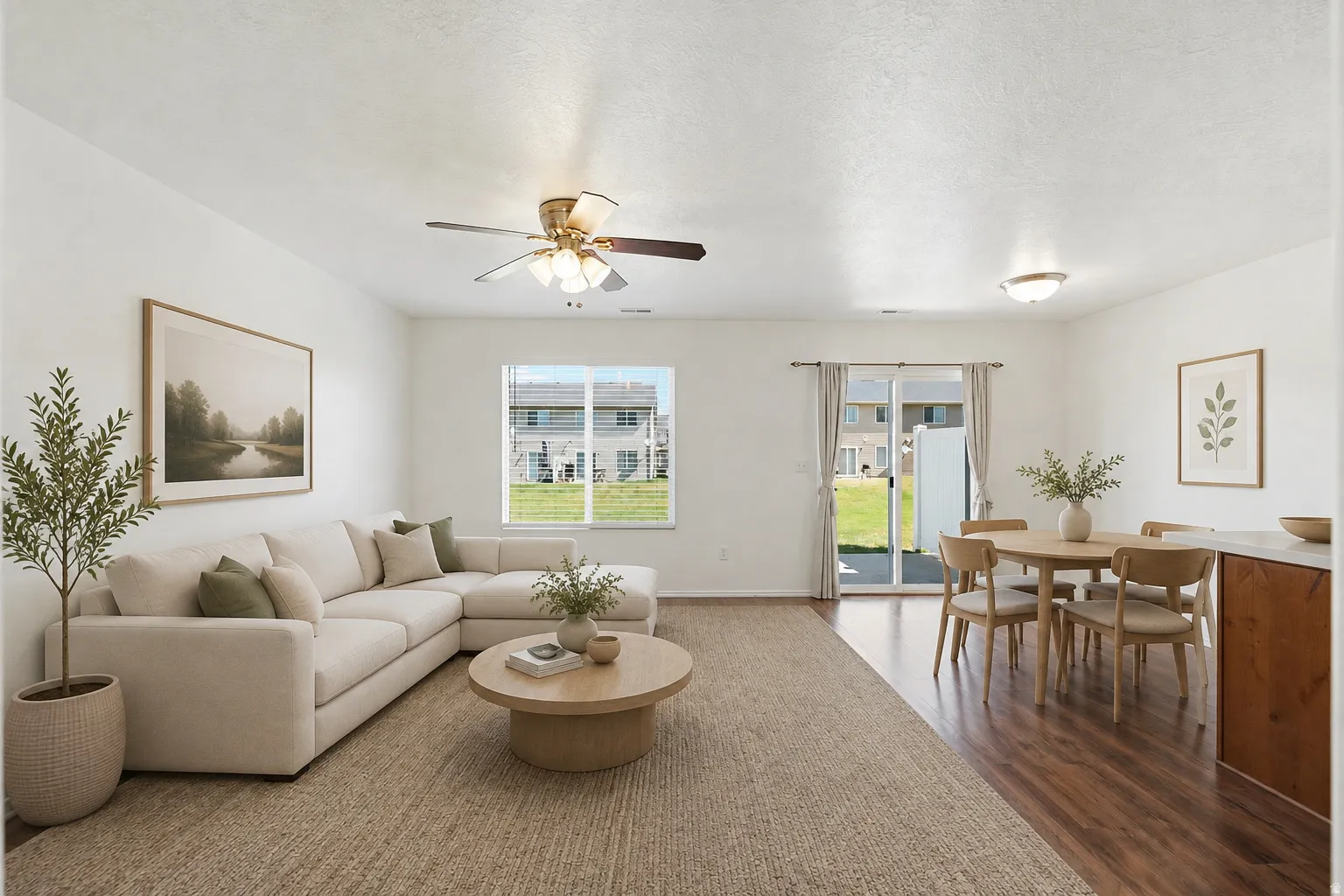 Open-concept living area featuring wood-finish flooring, a ceiling fan with integrated lighting, and a sliding glass door leading to the exterior