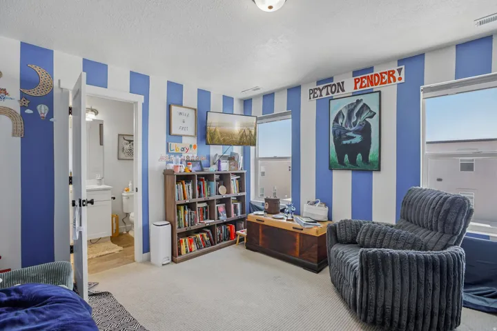 Carpeted interior with two windows featuring roller shades and a built-in bookshelf