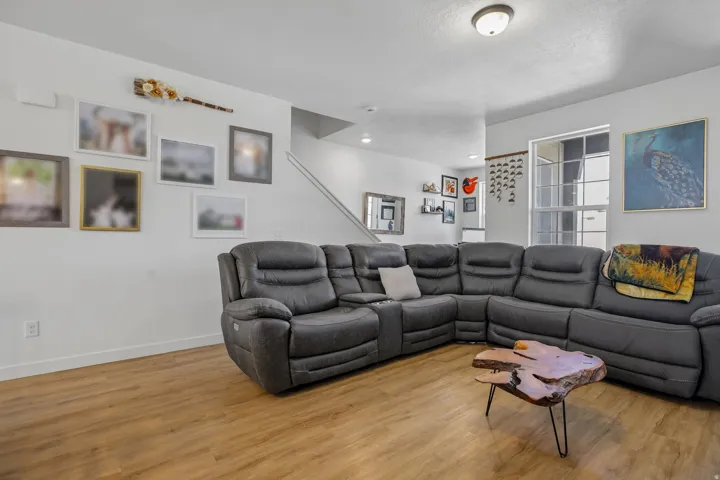 Spacious living area featuring wood-finish flooring, white baseboards, and ample natural light from a multi-pane window