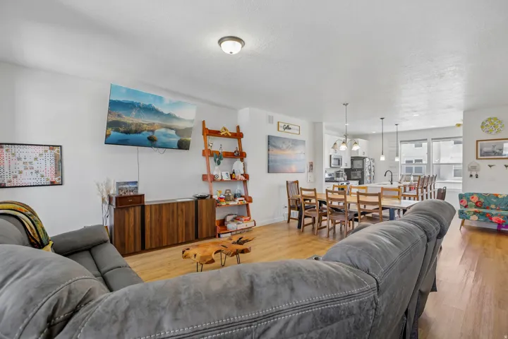 Open-concept living area featuring wood-finish flooring, a contemporary entertainment console, and recessed ceiling lighting