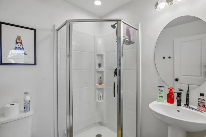 Shower enclosure with clear glass paneling and white tile-look surround