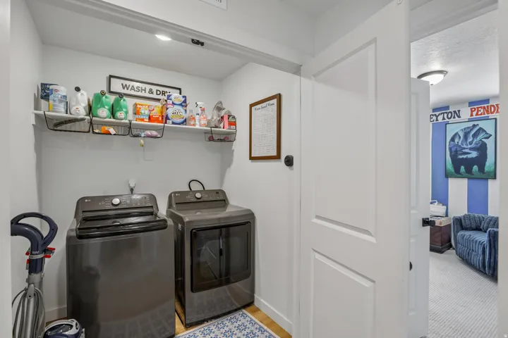 Dedicated laundry area featuring a built-in shelf with integrated wire baskets and wood-finish flooring