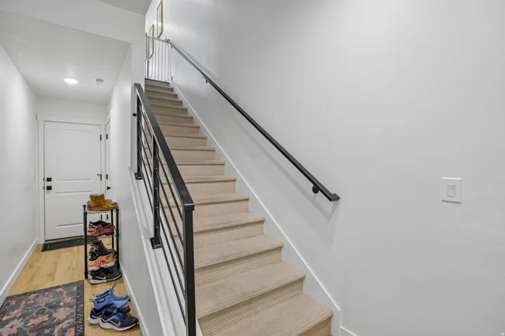 Carpeted staircase with contemporary metal railings and a black handrail