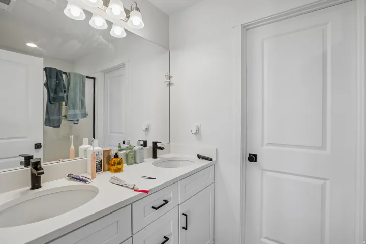 Double vanity featuring white cabinetry, light-toned countertops, and dual undermount sinks with matte black fixtures
