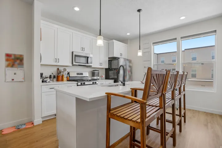 Contemporary kitchen featuring white cabinetry, a large center island with seating, stainless steel appliances, and wood-finish flooring