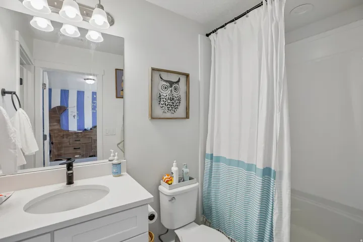 Bathroom featuring a vanity with a white countertop and undermount sink, matte black faucet, wall-mounted mirror, and a built-in bathtub with shower