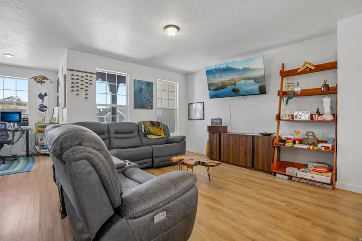 Open-concept living area featuring light wood-finish flooring, white walls, and multiple windows