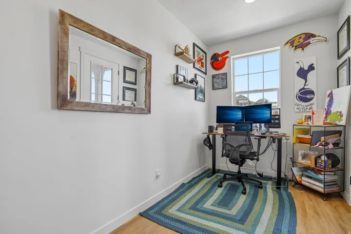 Dedicated room featuring light-toned walls, wood-finish flooring, and a large window providing ample natural light