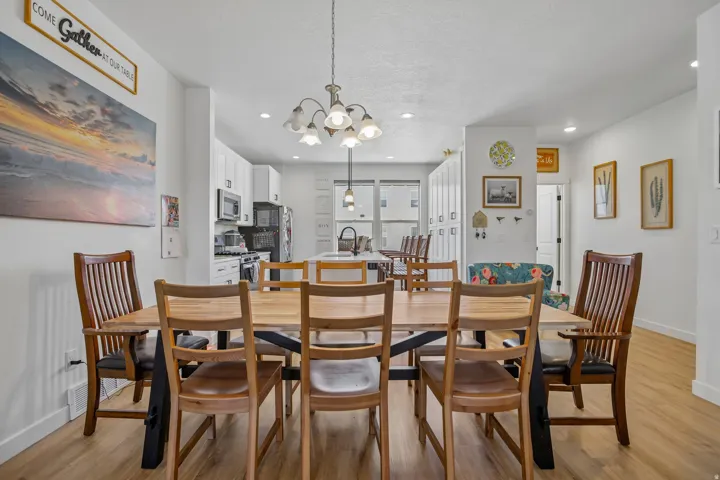 Open-concept floor plan featuring wood-finish flooring, a dining area with a chandelier, and a kitchen with white cabinetry