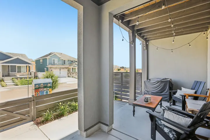 Covered patio featuring a concrete floor, slatted wood fencing, and string lighting